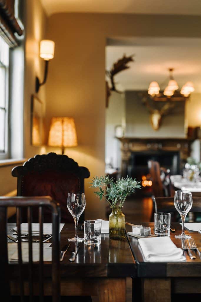 A cosy restaurant with a table set for a meal and a fire in the background.