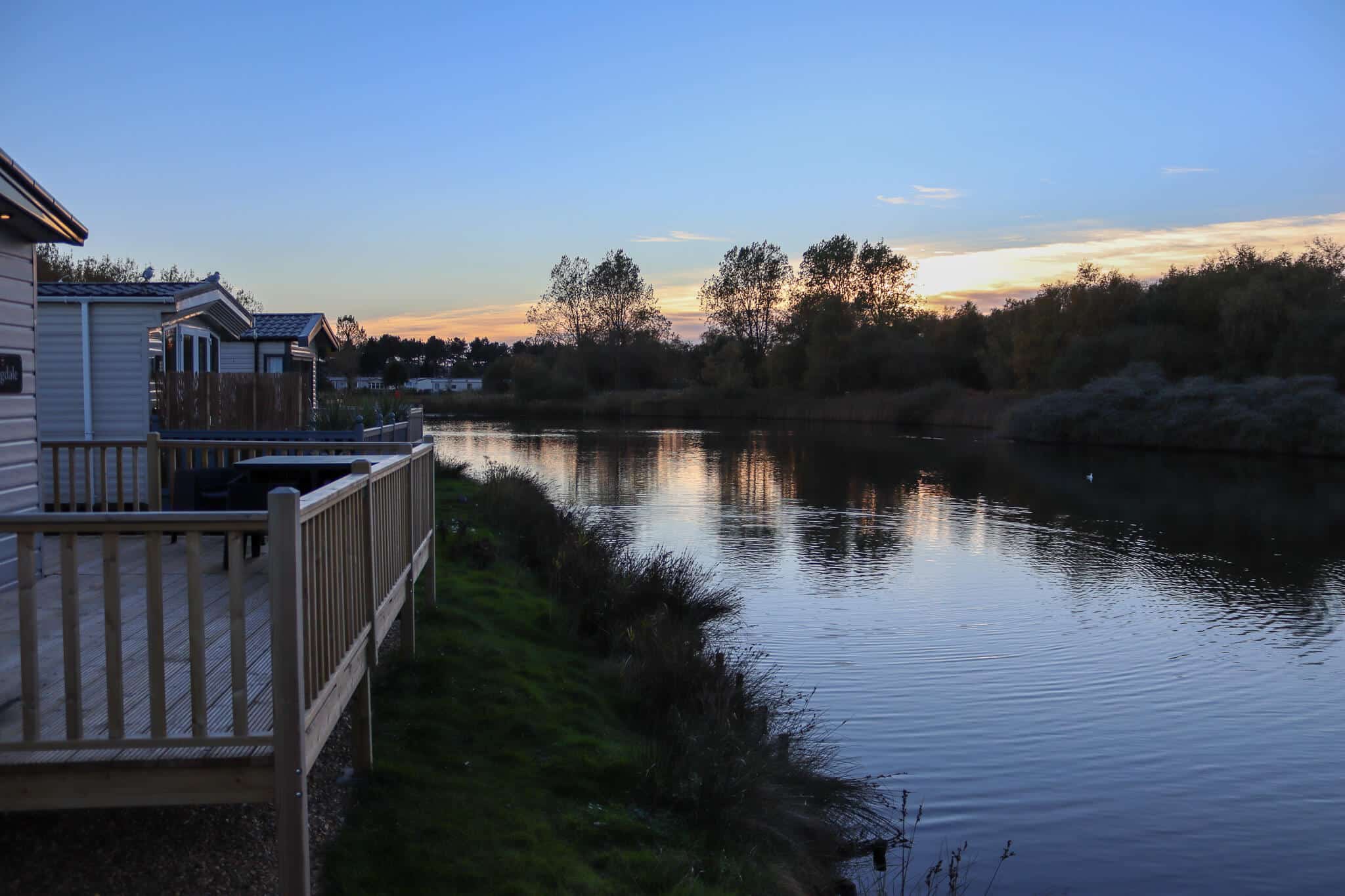 A sunset over a lake taken from the decking of a caravan.