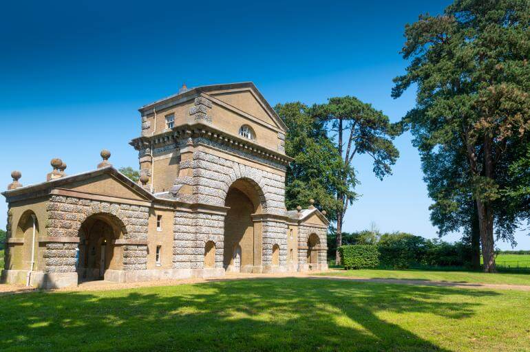 The Triumphal Arch at Holkham against a bright blue sky.